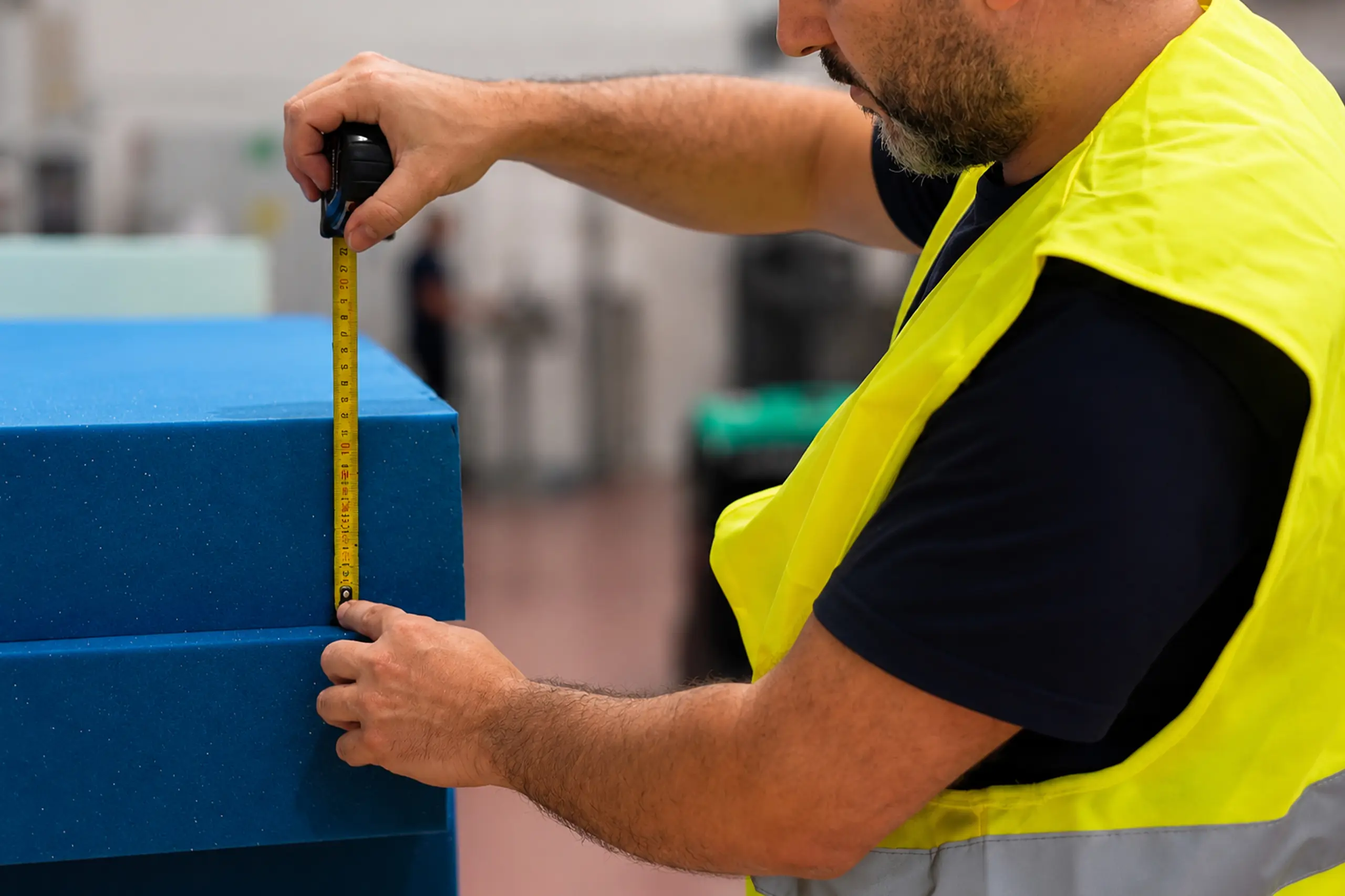 Un operaio siervo plast misura una lastra per materassi con un metro.